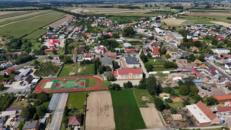Fotografia lotnicza przedstawiająca budynek szkoły wraz z obiektem sportowym obok.