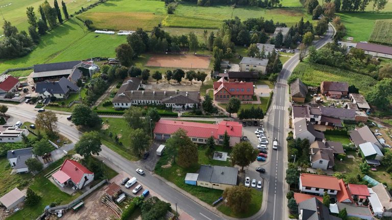 Fotografia z drona przedstawiająca budynek szkoły w otoczeniu lokalnej infrastruktury.