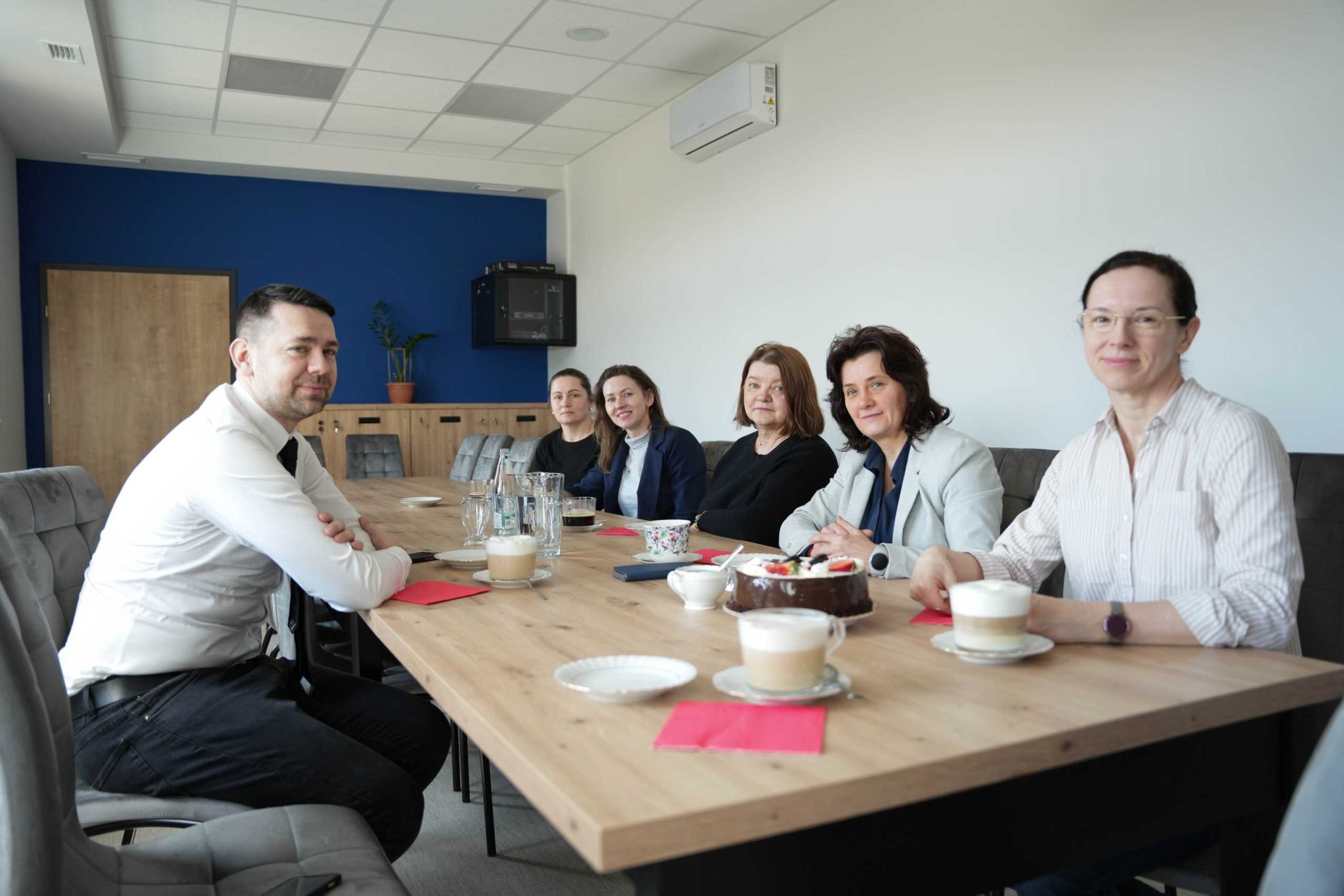 Grupa osób siedząca przy stole, po jednej stronie Burmistrz, po drugiej kobiety