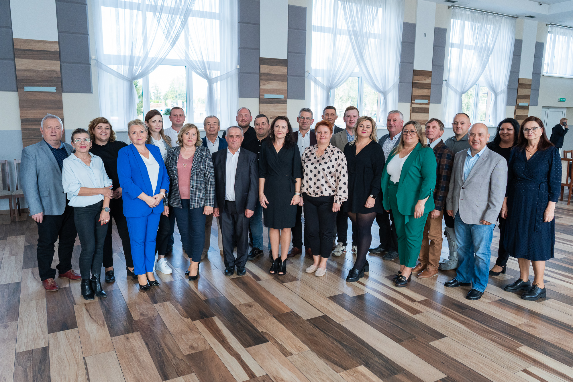 Grupa osób w eleganckich ubraniach stoi wewnątrz pomieszczenia